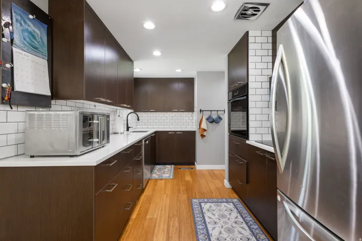 Kitchen with stainless steel appliances, dark wood finish cabinets, light wood-type flooring, recessed lighting, and modern cabinets