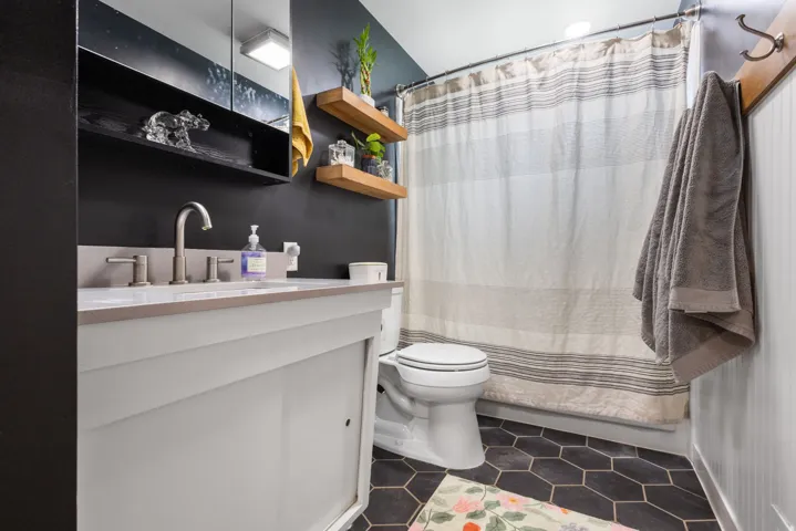 Bathroom with vanity, dark tile patterned flooring, and a shower with curtain