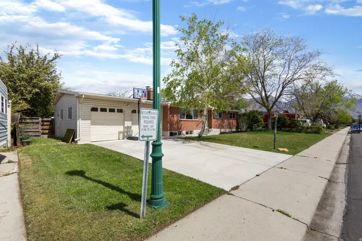 View of front of house with a front yard, concrete driveway, a chimney, and a garage