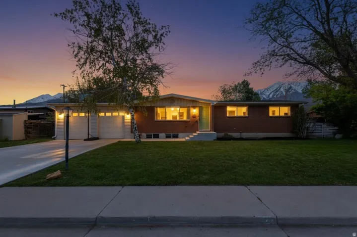 Ranch-style house with a garage, a lawn, concrete driveway, and brick siding