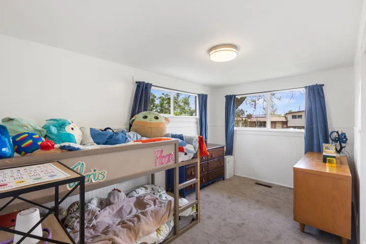 Bedroom with light colored carpet and a wainscoted wall