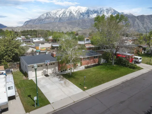 View of front of property featuring a front lawn, a mountain view, a residential view, and concrete driveway