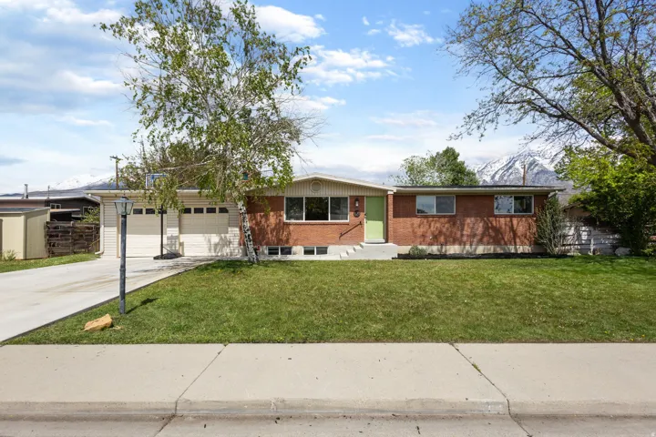 Ranch-style house featuring brick siding, a front lawn, concrete driveway, and a garage