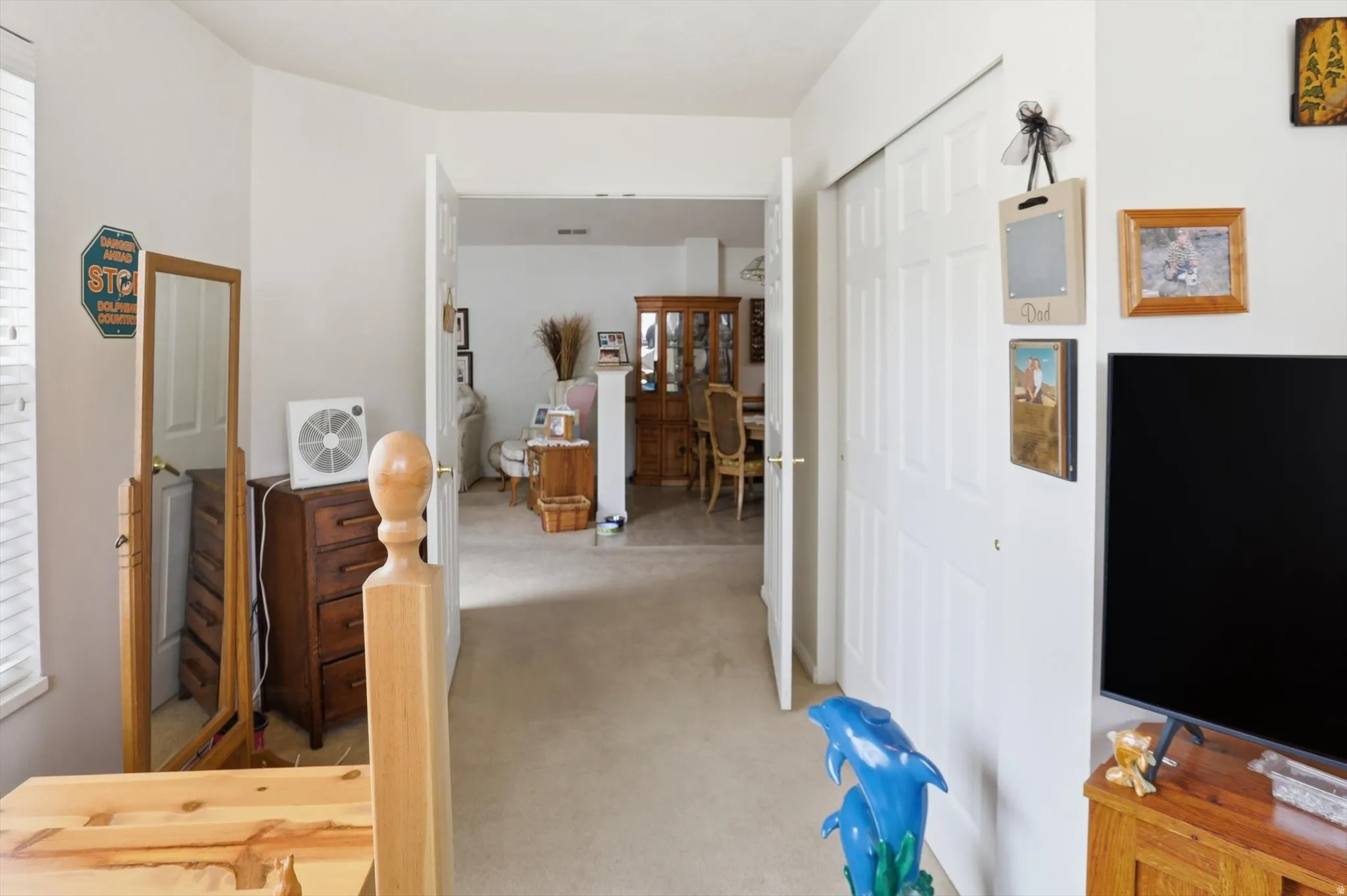 Interior hallway with light beige carpeting and white walls, featuring a white bi-fold closet door