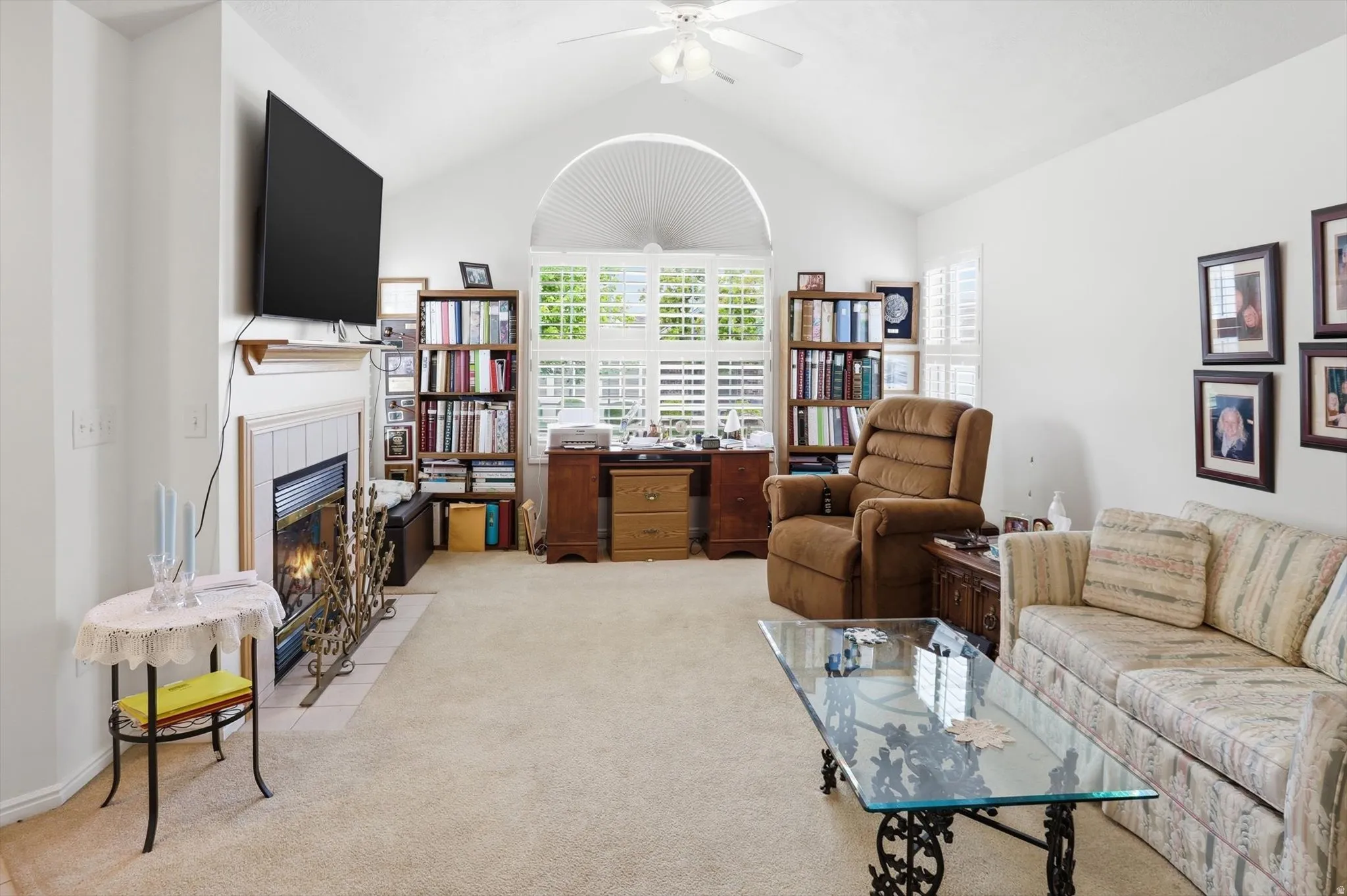 Living area featuring a vaulted ceiling and a fireplace with a white tile surround