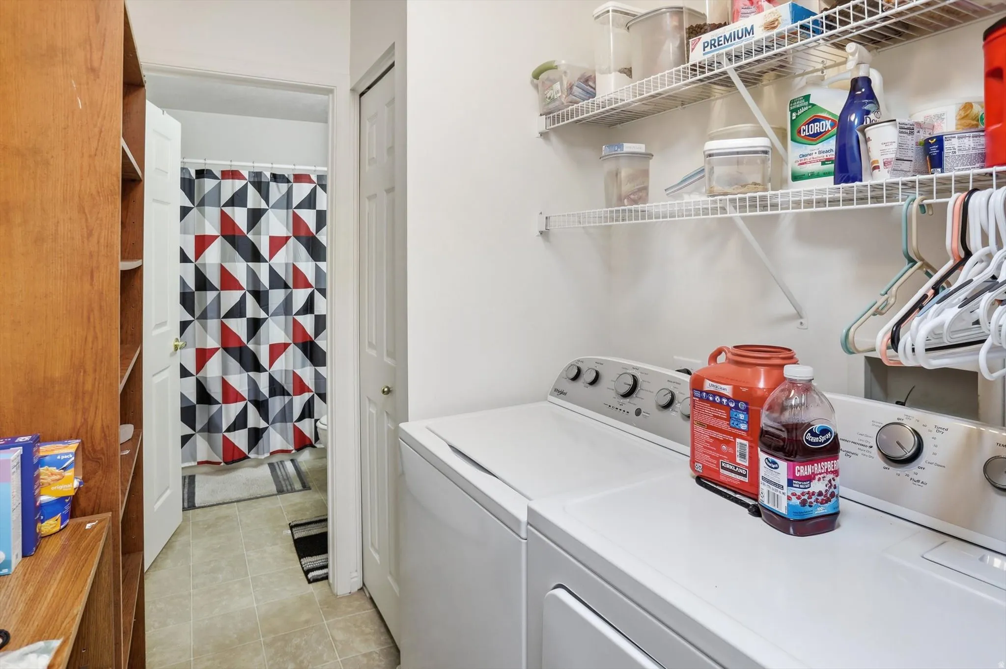 Dedicated laundry area featuring a washer and dryer, accompanied by wire shelving for storage