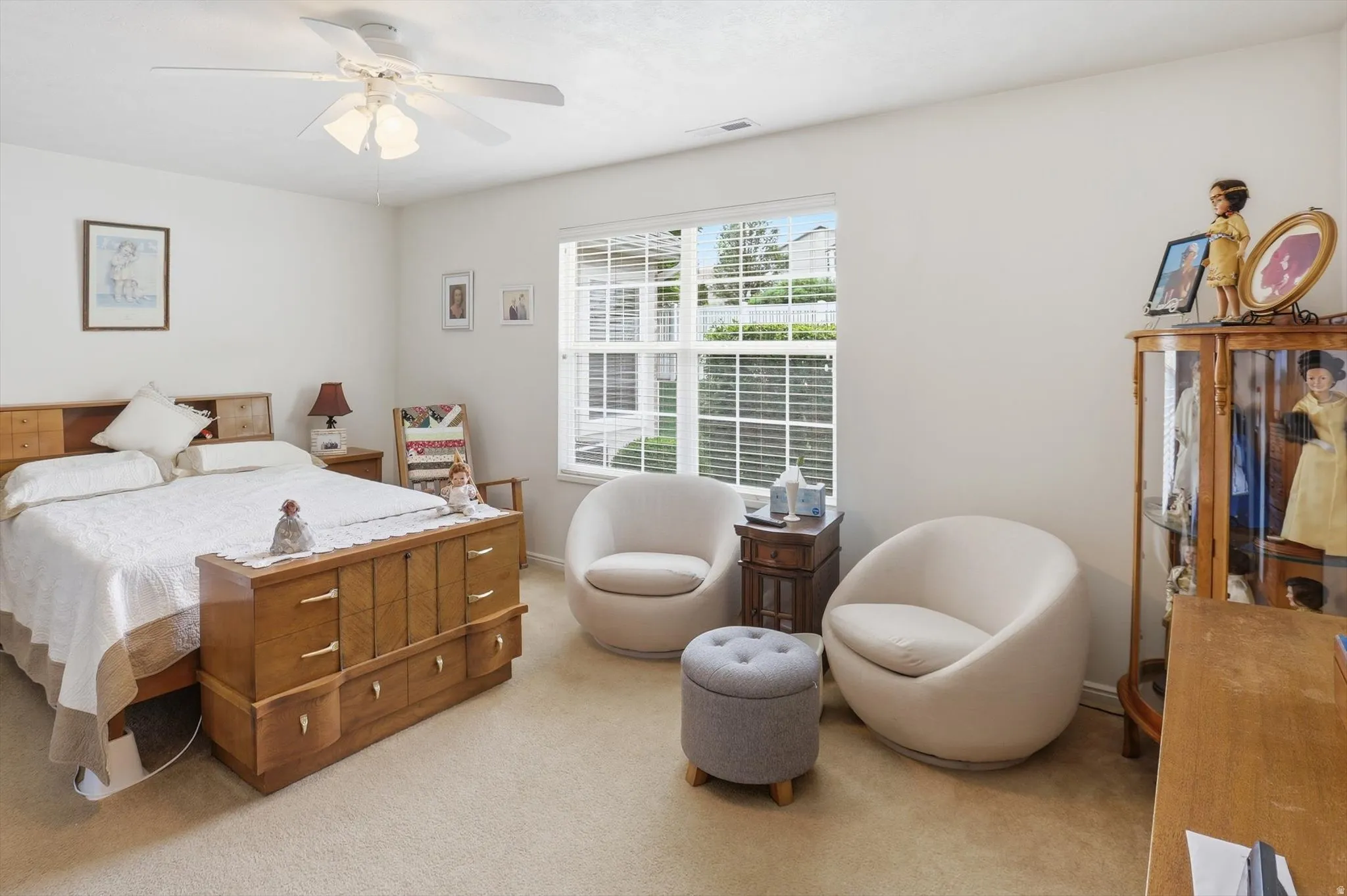 Carpeted bedroom with a window featuring horizontal blinds, a ceiling fan with integrated lighting, and white wall finishes