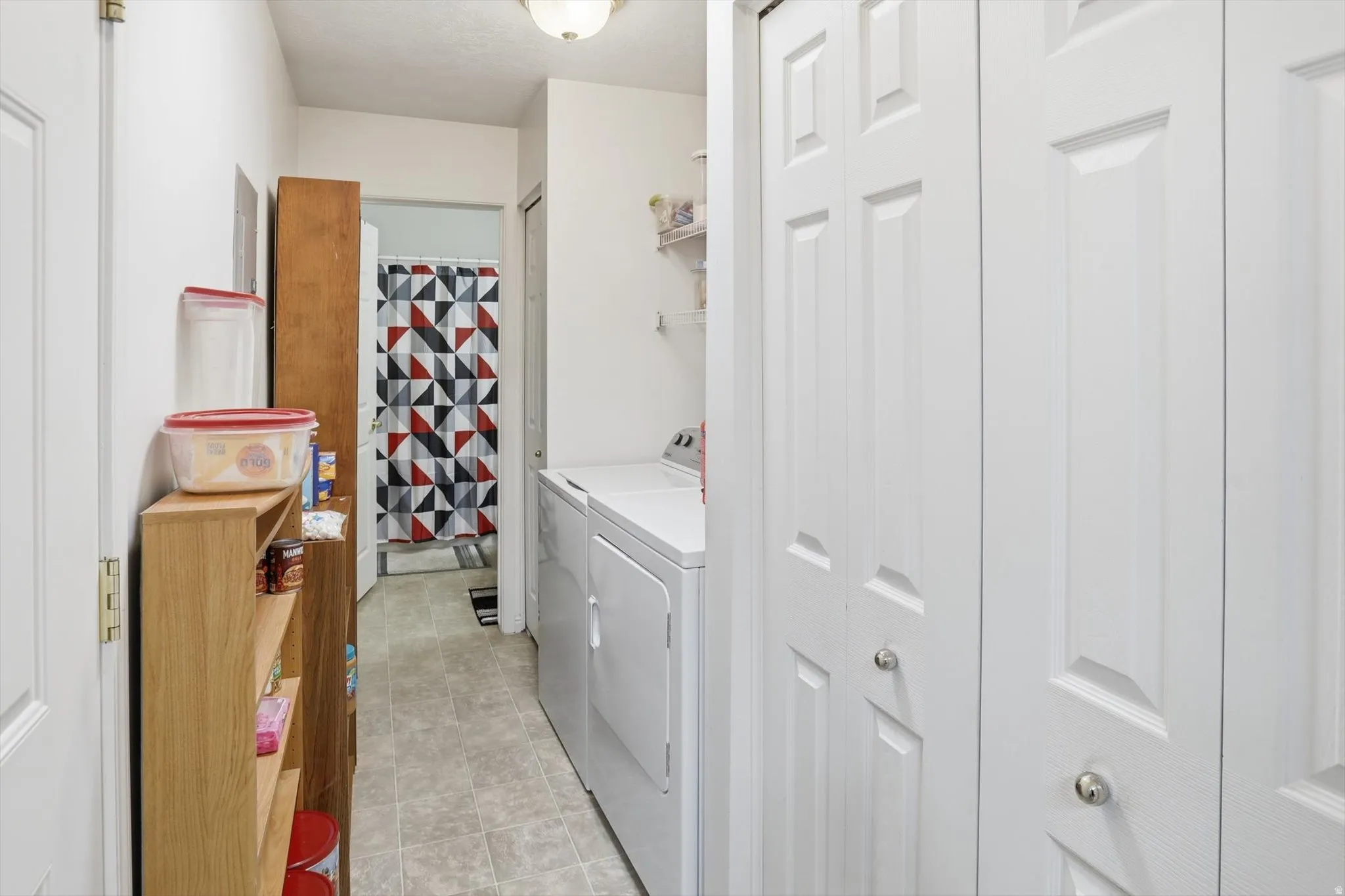 Dedicated laundry area with a white washing machine and dryer, featuring white bi-fold doors