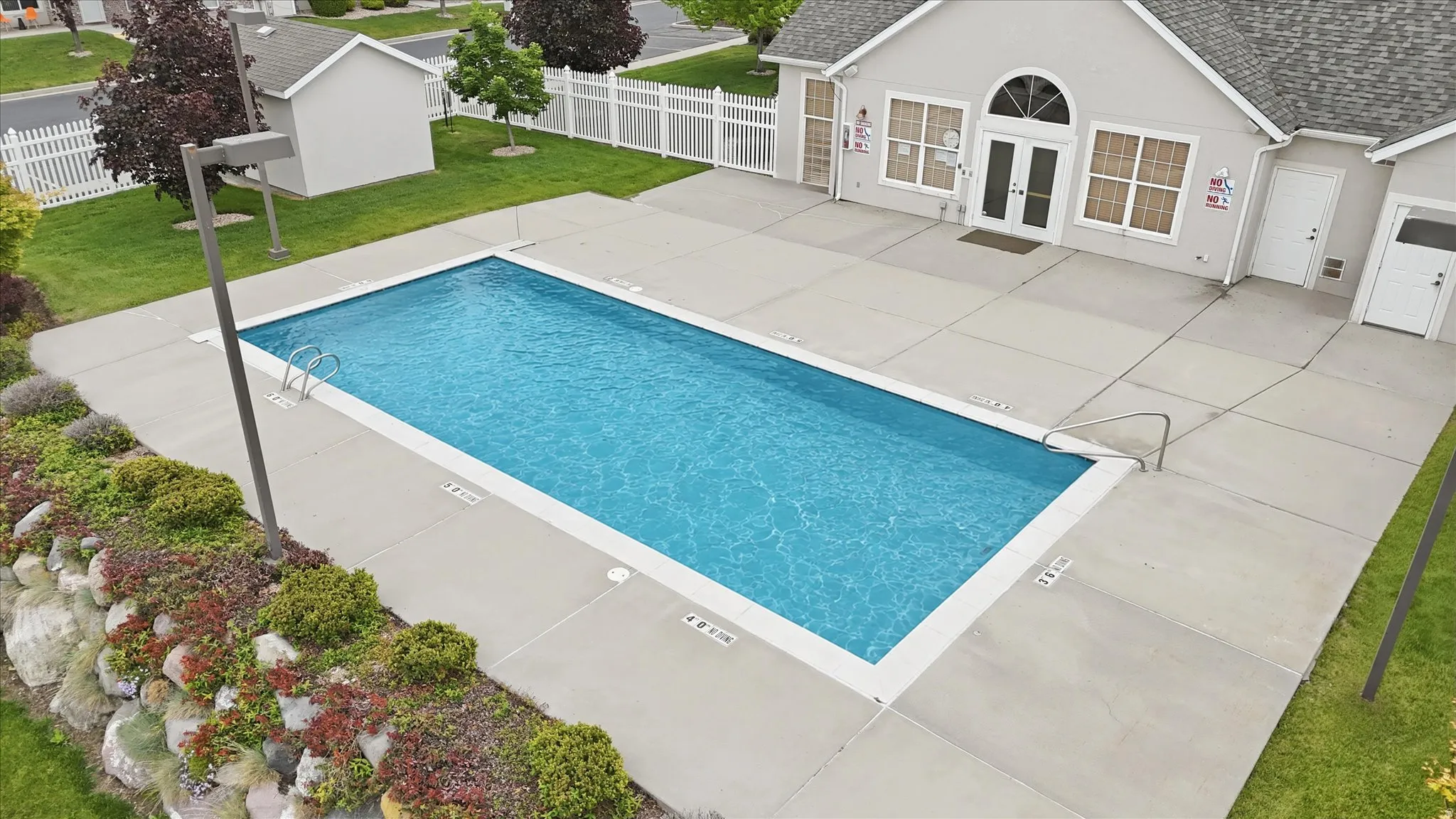 Rectangular swimming pool with integrated steps and handrails, surrounded by a concrete patio