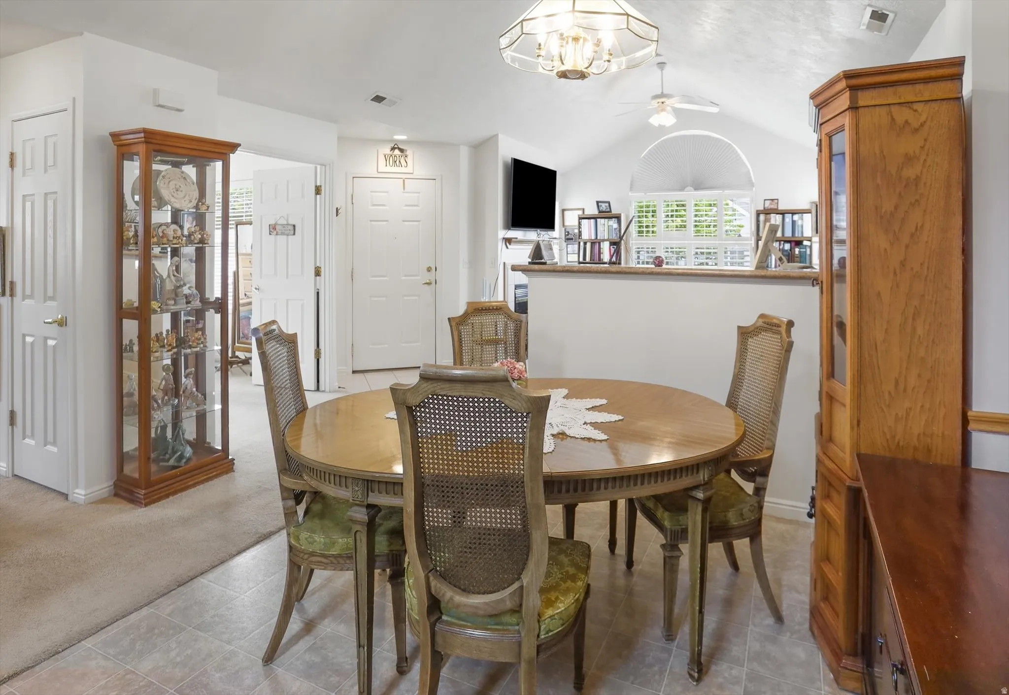 Vaulted ceiling with an arched window, white paneled doors, and light-toned flooring