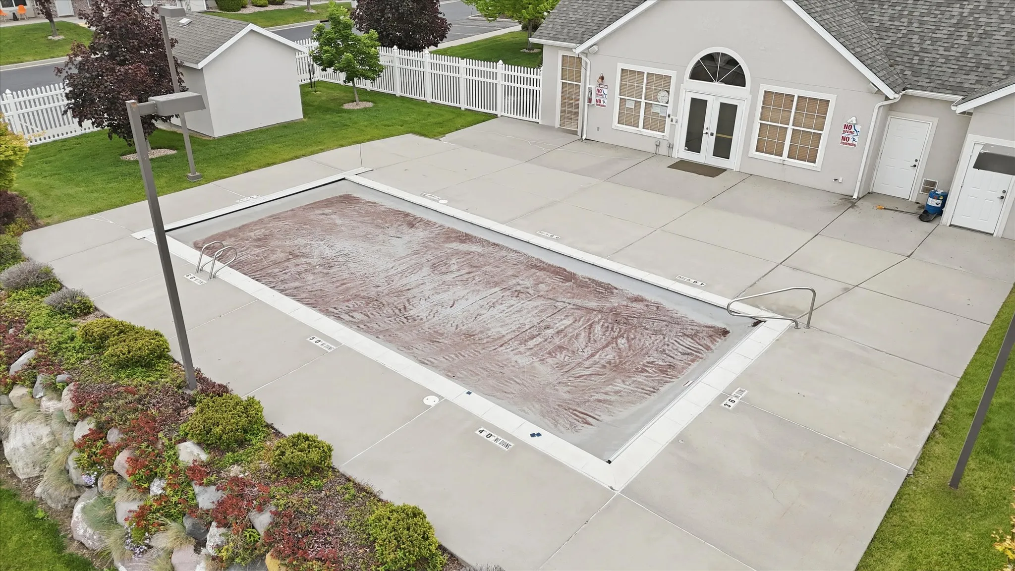Outdoor swimming pool with a protective cover, surrounded by a concrete deck