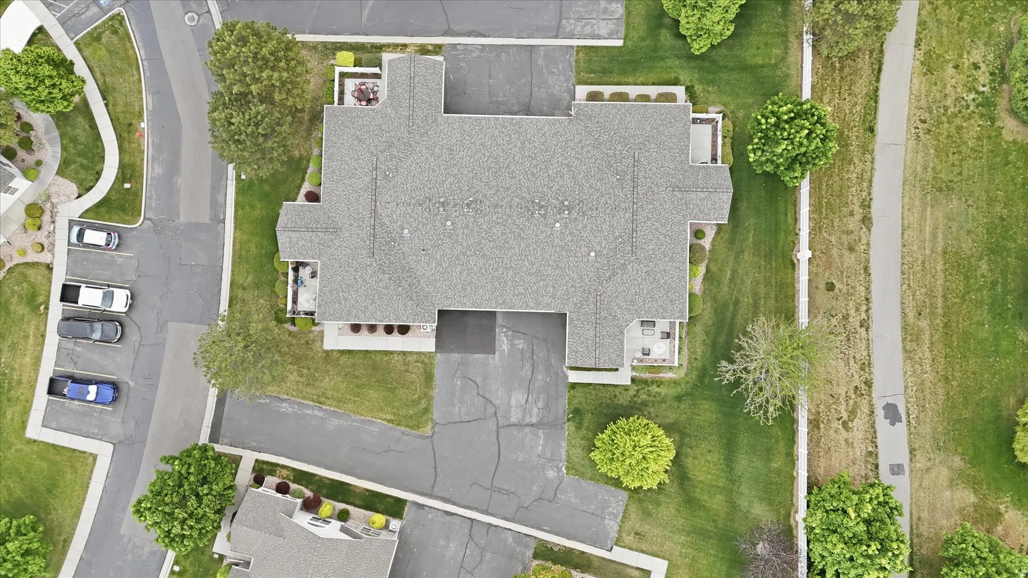 Residential building with a shingled roof, surrounded by green lawns and mature trees