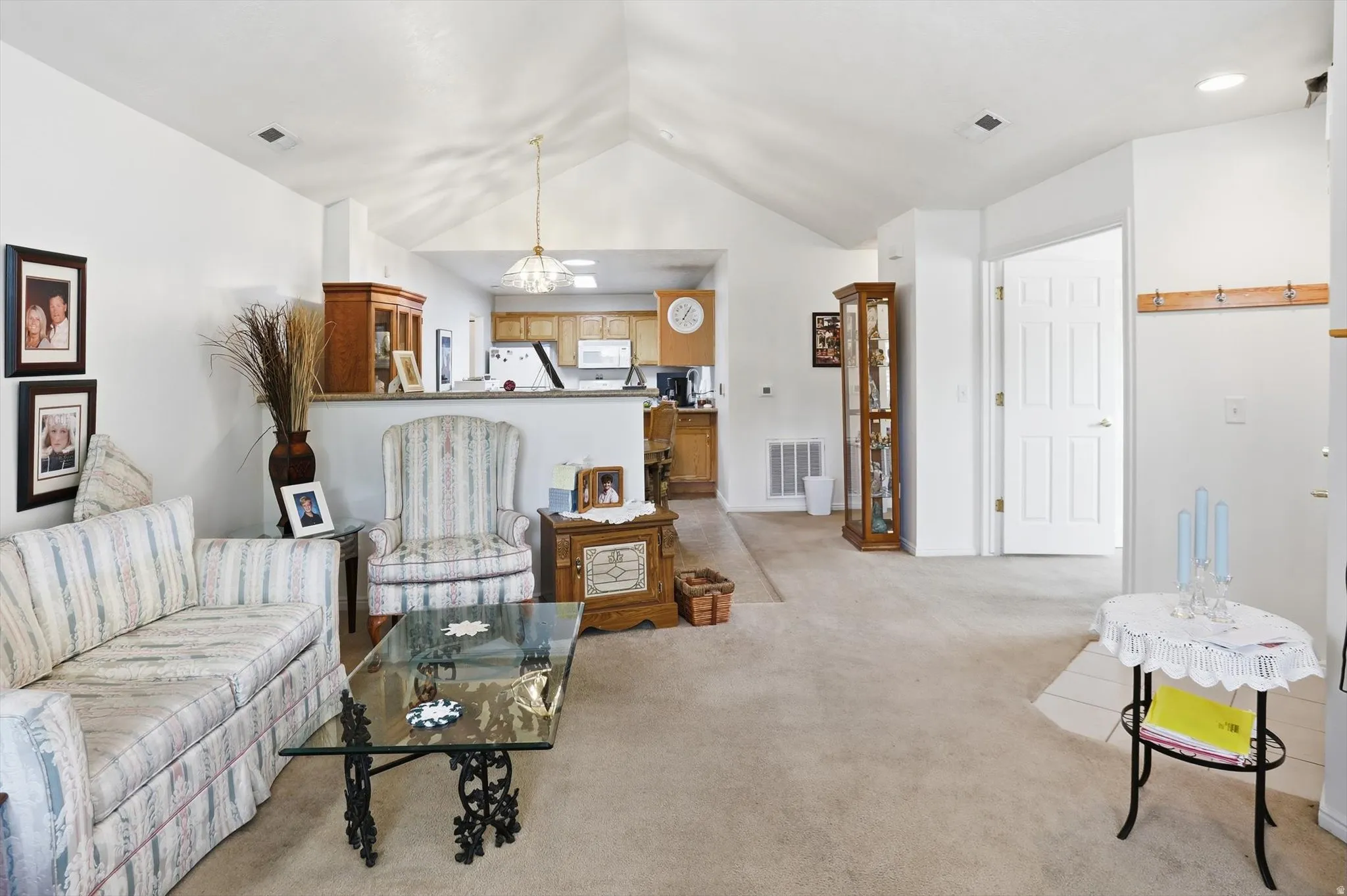 Spacious living area featuring neutral carpeting and vaulted ceilings