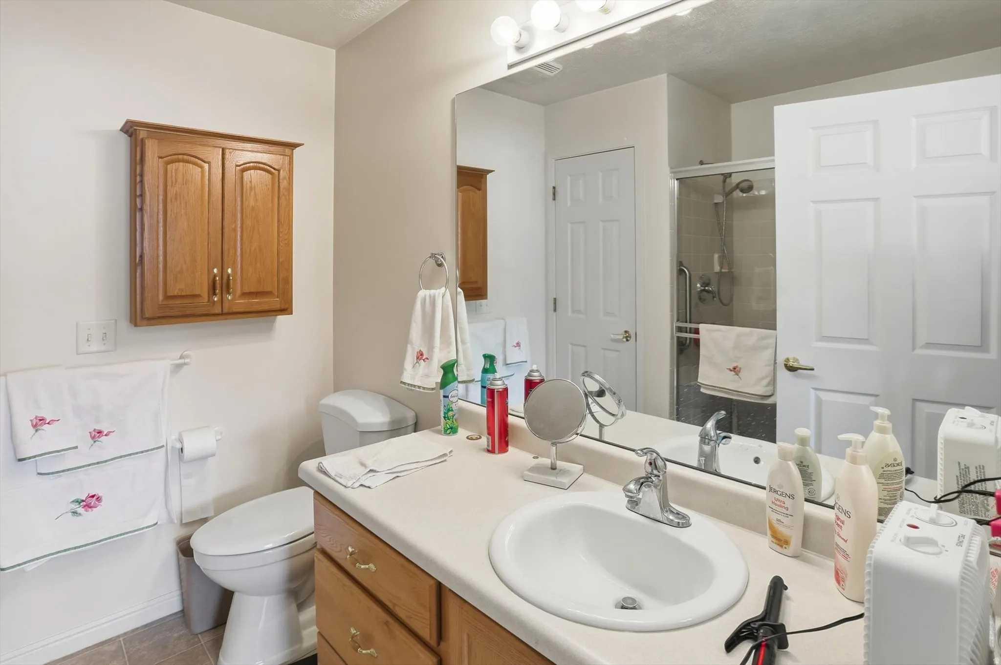 Bathroom featuring a single vanity with an integrated sink, polished chrome faucet, and wood-finish cabinetry