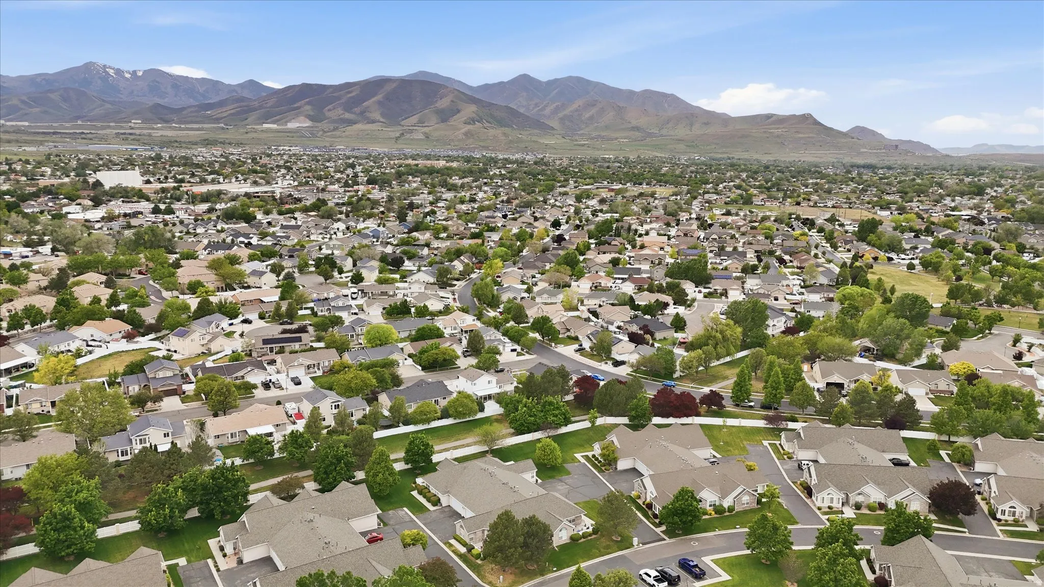 Residential community with a variety of architectural styles, mature trees, and mountainous terrain in the background