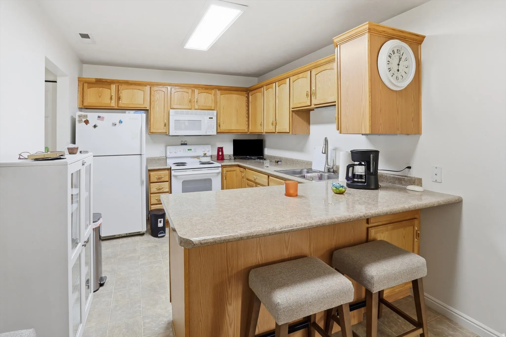 U-shaped kitchen featuring light wood cabinetry, a breakfast bar with built-in storage, and light-toned countertops