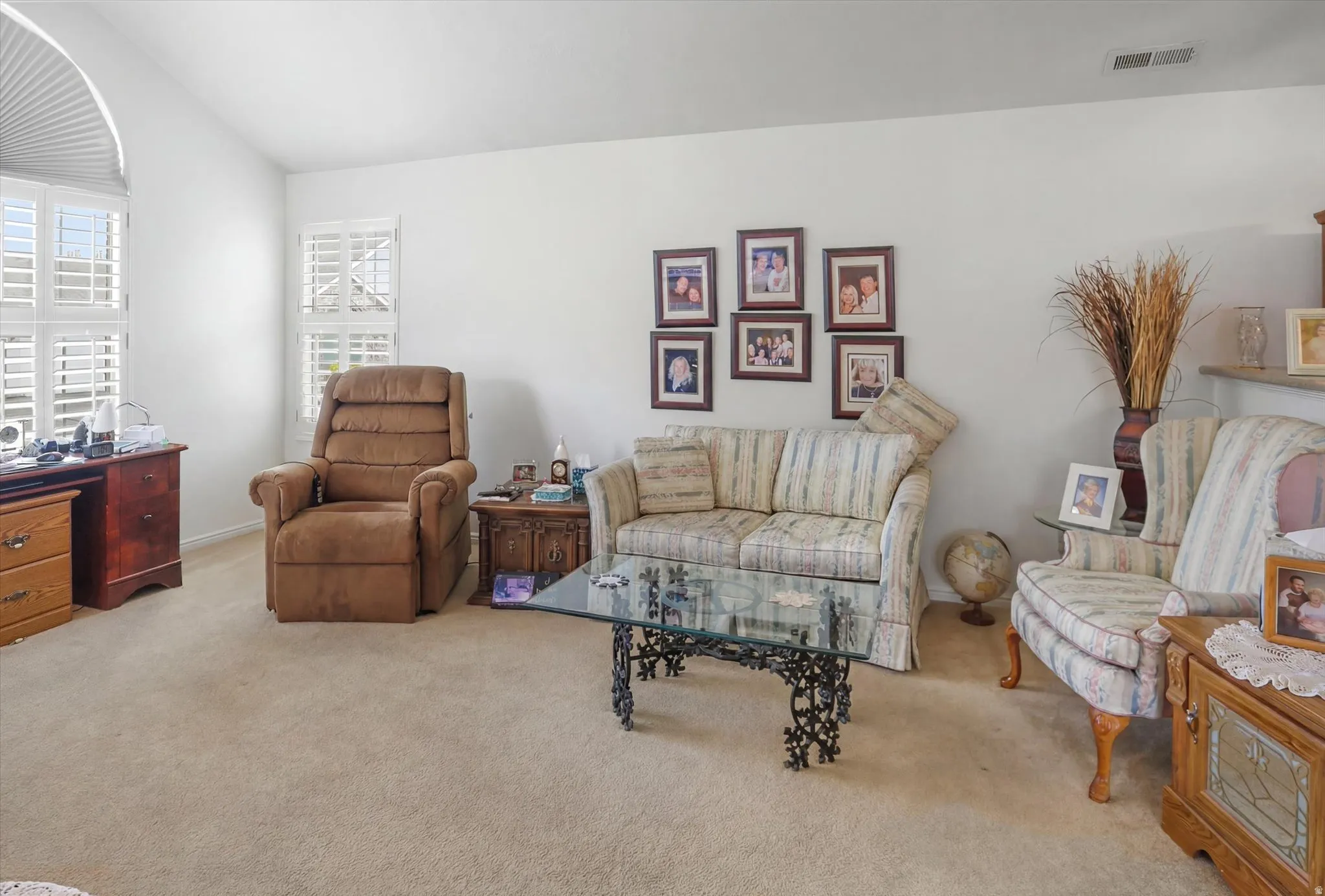 Living area featuring vaulted ceilings, plantation shutters, and plush carpet flooring