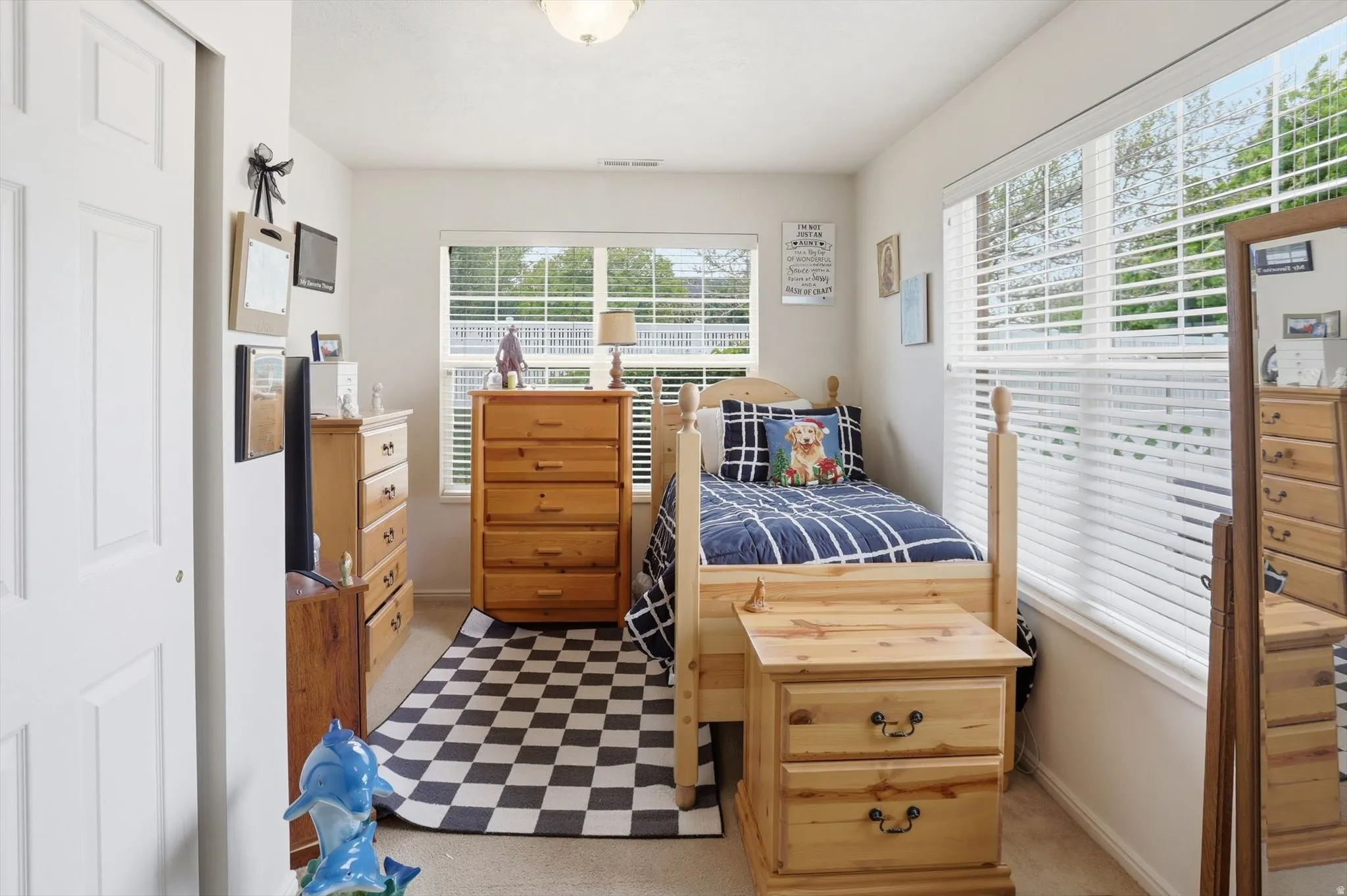 Bright bedroom featuring a large window with white blinds, a second window with white blinds, a semi-flush mount ceiling light, and a white bi-fold closet door