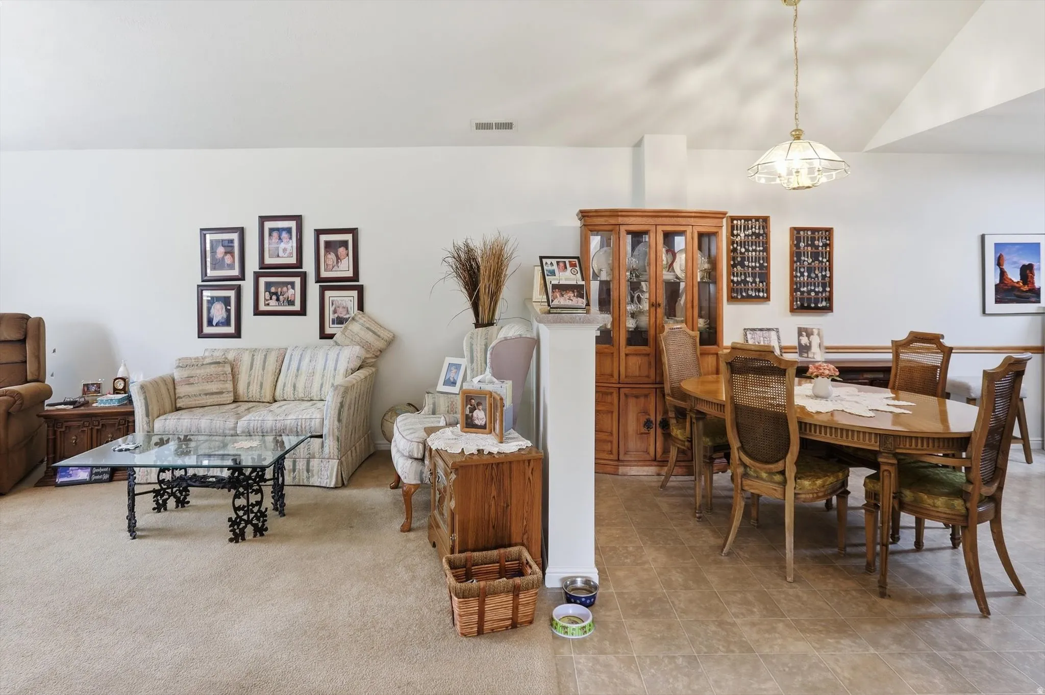 Spacious open-concept living and dining area featuring vaulted ceilings, neutral wall tones, and varied flooring