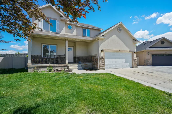 Traditional home featuring a porch, stucco siding, concrete driveway, and stone siding