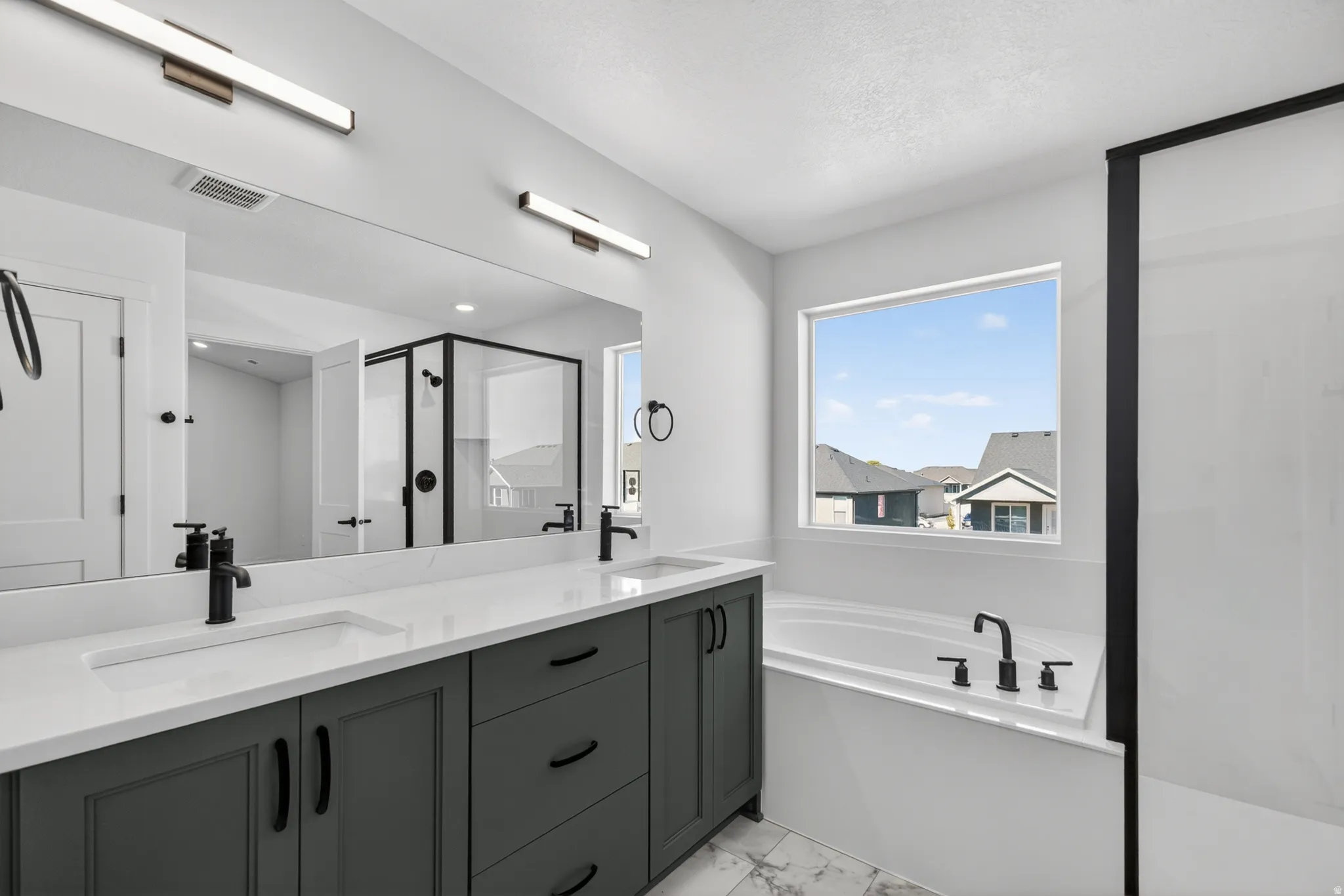Bathroom featuring a dual vanity with dark cabinetry, white countertops, and matte black fixtures