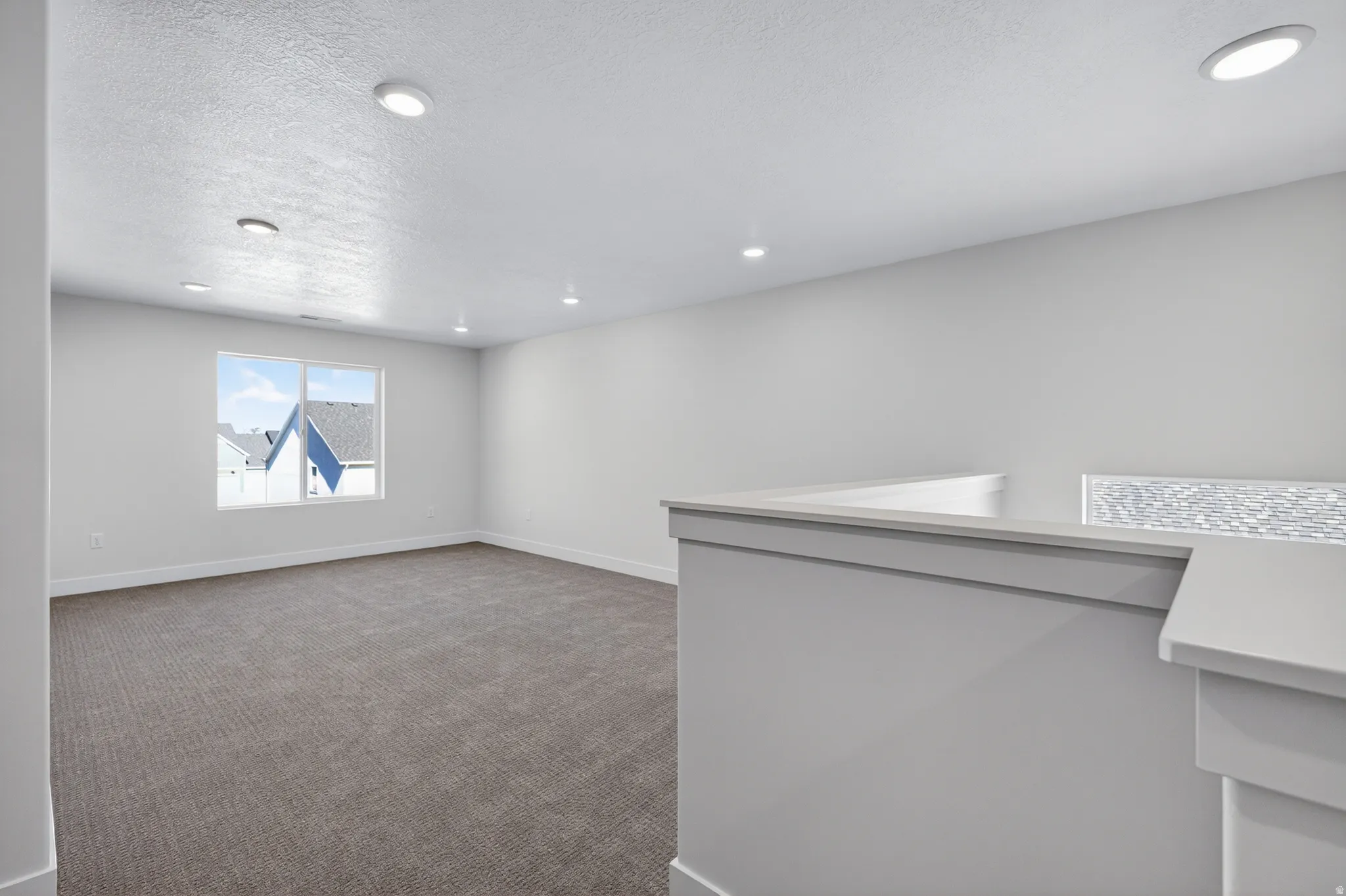Open concept room with neutral carpet, recessed lighting, and a large multi-pane window