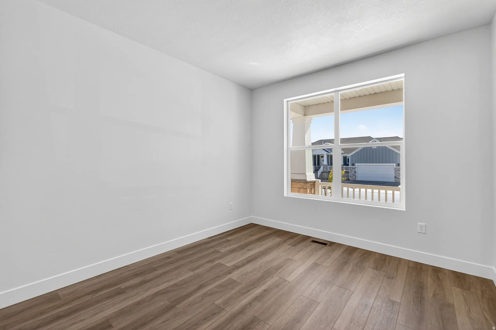 Room with wood-finish flooring, white baseboards, and a large window