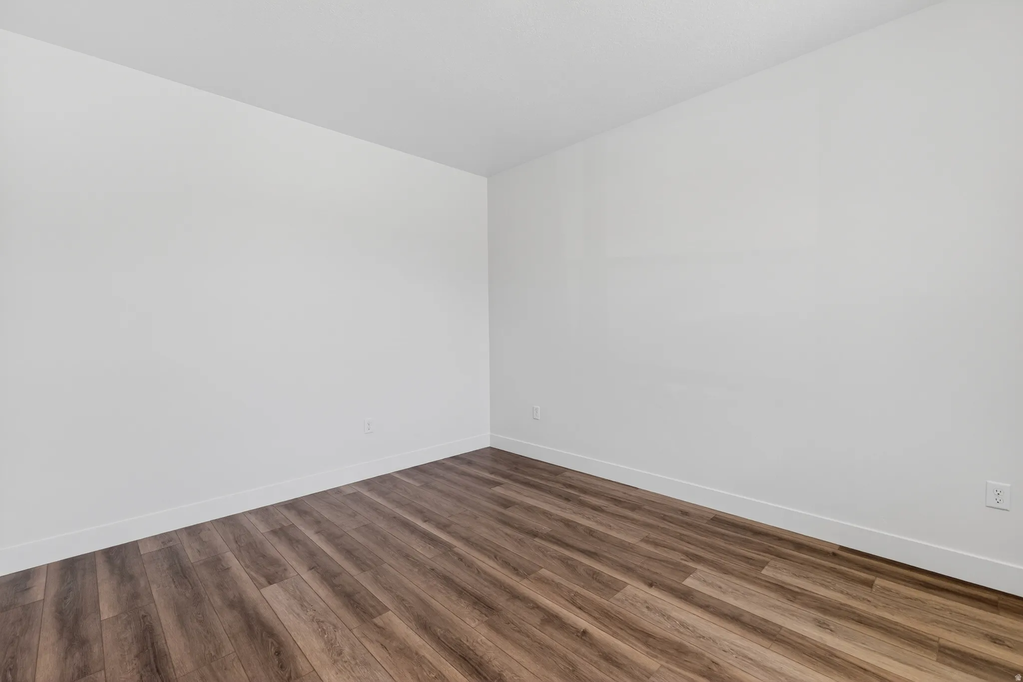 Room featuring wood-finish flooring, white baseboards, and neutral wall tones
