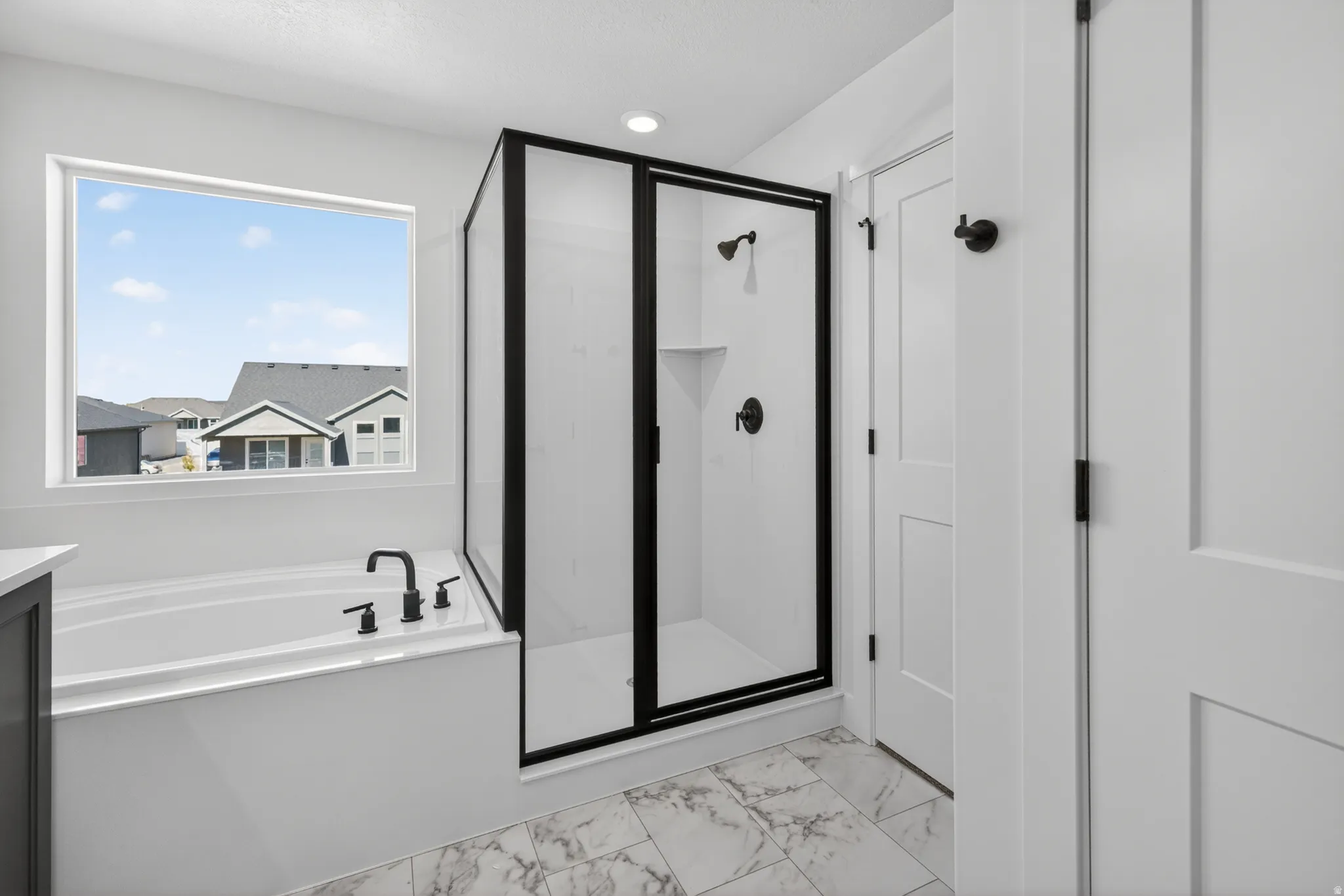 Bathroom featuring a built-in tub with matte black fixtures, a walk-in shower with a black-framed glass enclosure, white panel doors, recessed lighting, and marble-look floor tiles