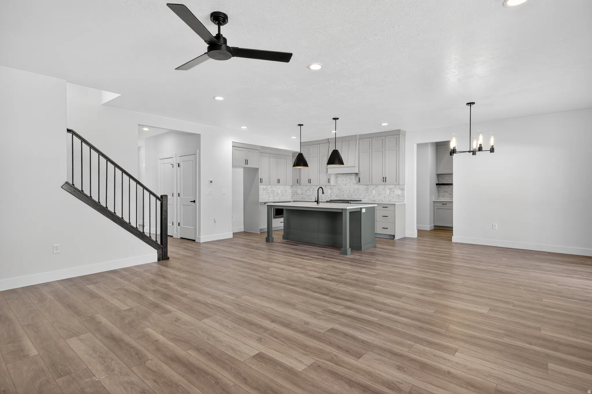 Open-concept living area featuring wood-finish flooring, a modern black ceiling fan, and recessed lighting