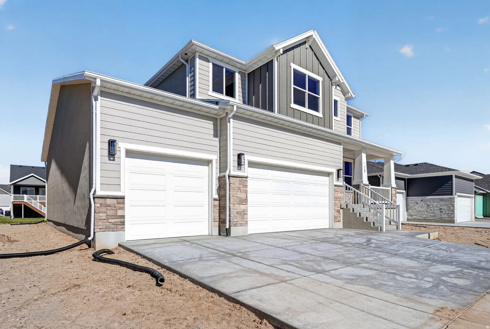 Newly constructed residence featuring a stone foundation, light gray siding, and a two-car garage