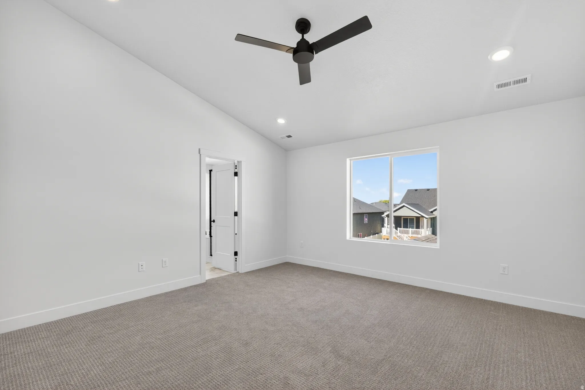 Spacious interior room featuring a large window, neutral carpeting, recessed lighting, and a contemporary ceiling fan