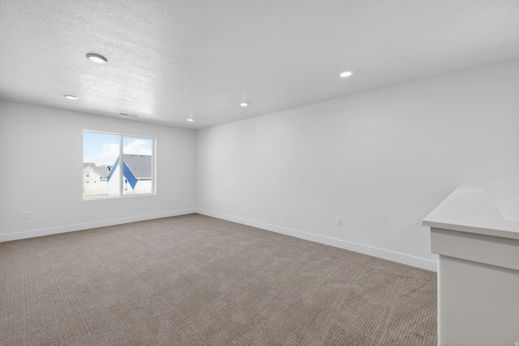 Spacious room featuring neutral carpet flooring, white walls, and recessed lighting