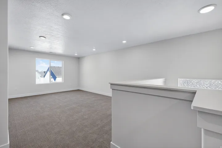 Open concept room with neutral carpet, recessed lighting, and a large multi-pane window