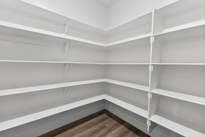 Expansive pantry featuring multi-level shelving, white finishes, and wood-finish flooring