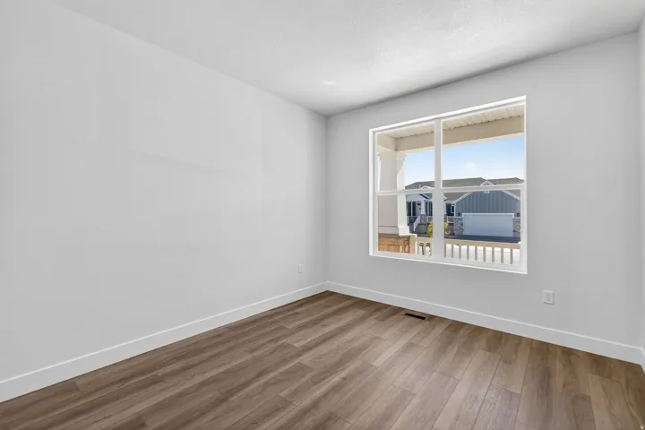 Room with wood-finish flooring, white baseboards, and a large window