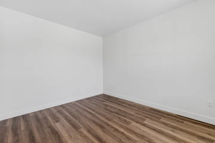 Room featuring wood-finish flooring, white baseboards, and neutral wall tones