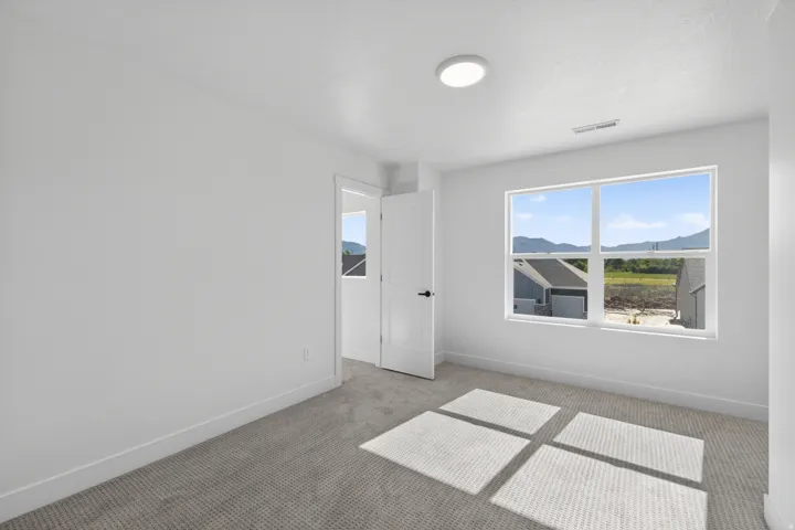 Bright interior space featuring a large window, light-colored walls, and gray patterned carpet