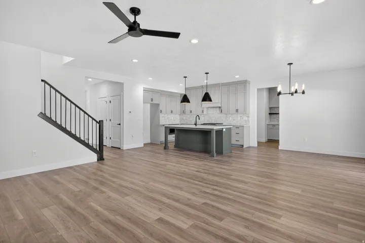 Open-concept living area featuring wood-finish flooring, a modern black ceiling fan, and recessed lighting