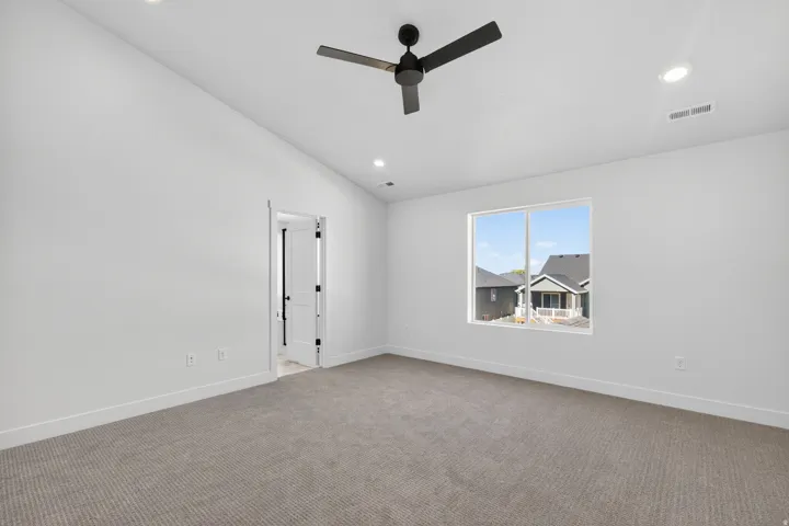 Spacious interior room featuring a large window, neutral carpeting, recessed lighting, and a contemporary ceiling fan