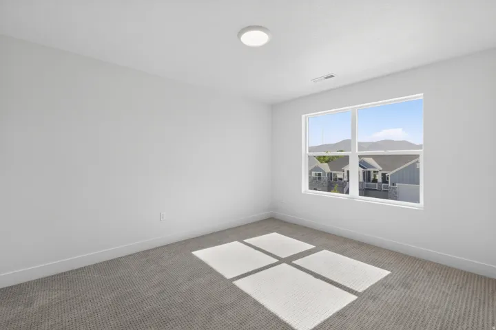 Carpeted room featuring a large window, white walls, white trim, and a flush-mount ceiling light