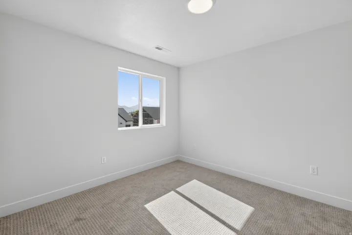 Carpeted room featuring a single window, white walls, and a flush-mount ceiling light