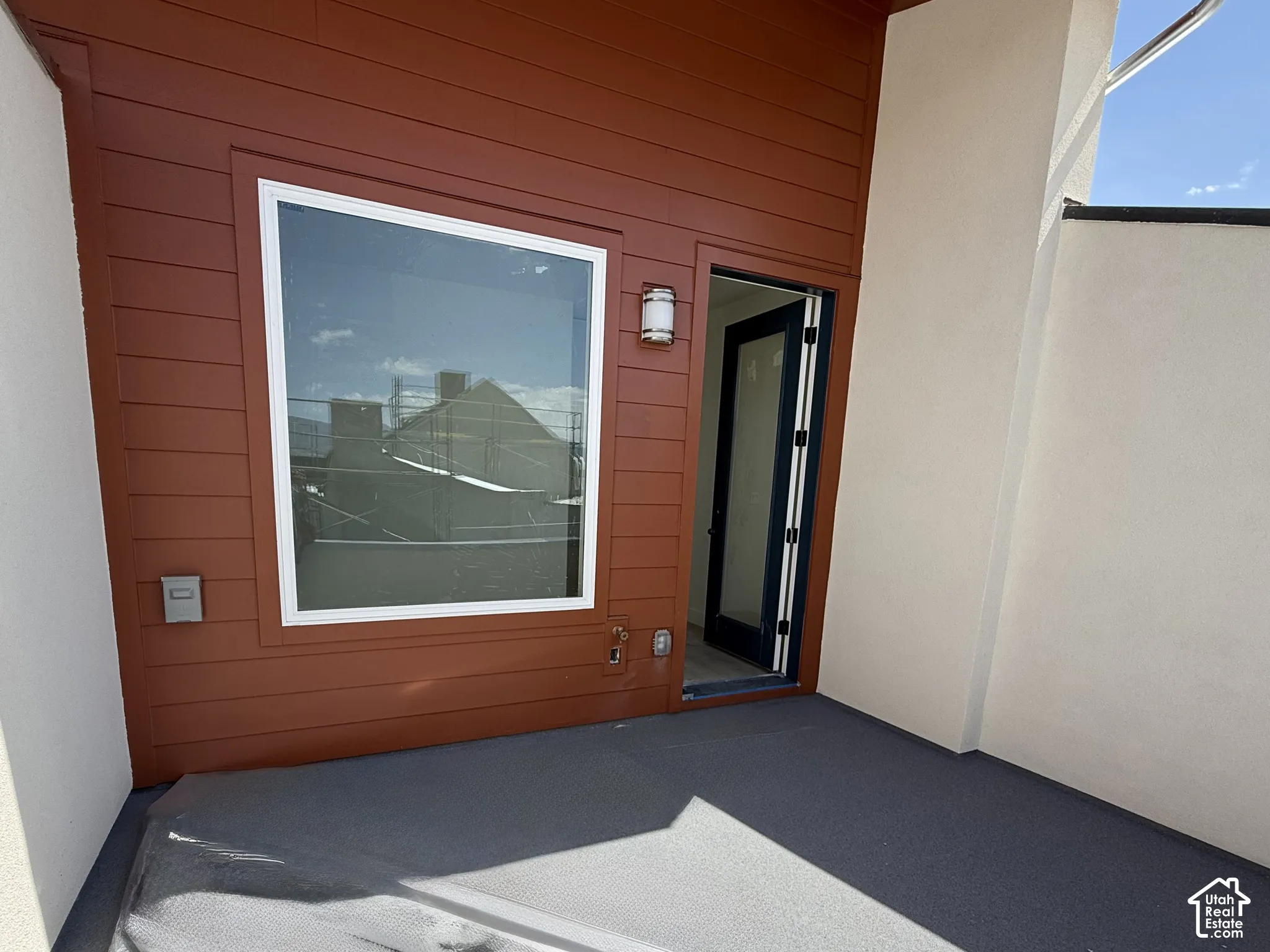 Private balcony featuring durable flooring, exterior wall lantern, large window, and access door