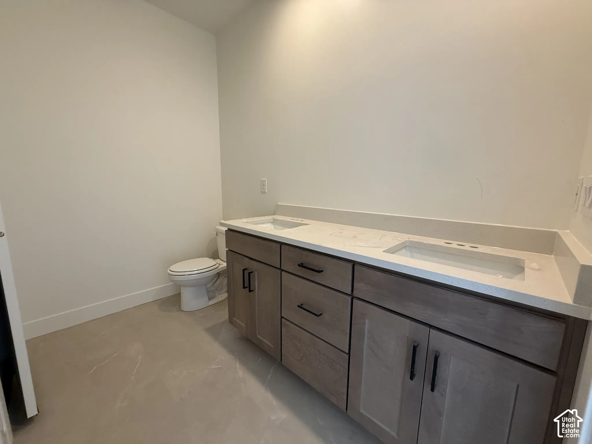 Double vanity with integrated sinks, light-toned countertop, and wood-finish cabinetry featuring matte black hardware