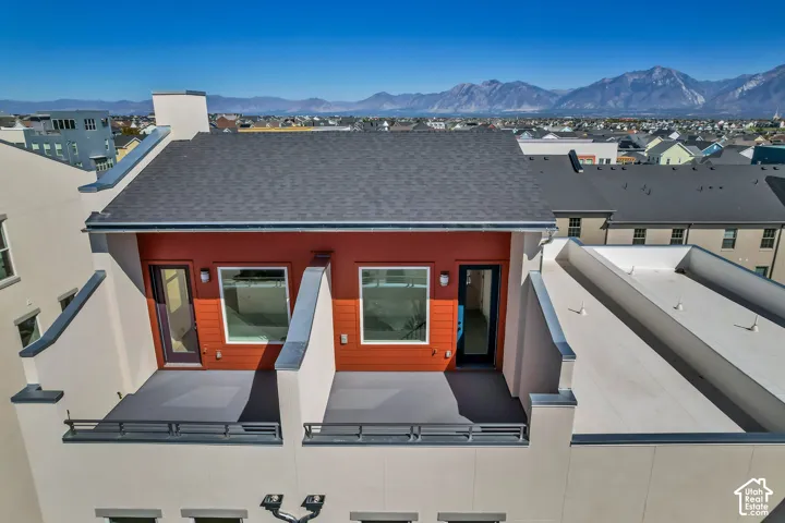 Upper-level balconies with dark gray railings, red paneling, and a distinct mountain backdrop