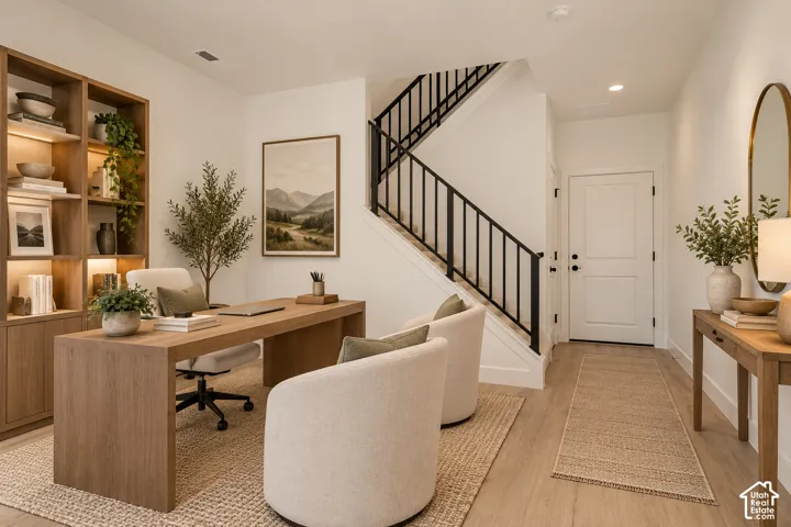 Wood-finish flooring, built-in shelving with integrated lighting, and a staircase with a black wrought iron railing