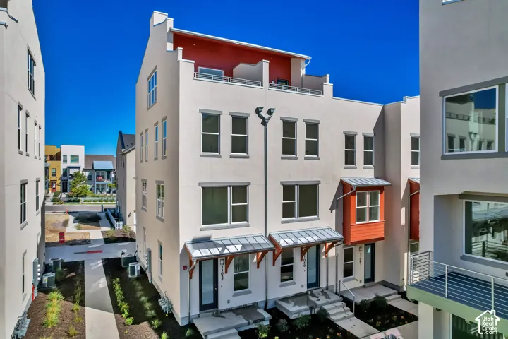 Modern townhome exterior featuring stucco siding, multiple windows, and a private rooftop terrace