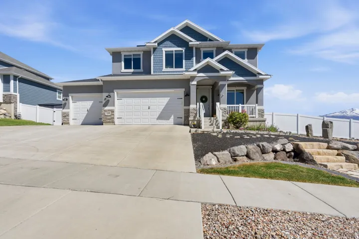 Craftsman inspired home with stone siding, driveway, covered porch, and an attached garage
