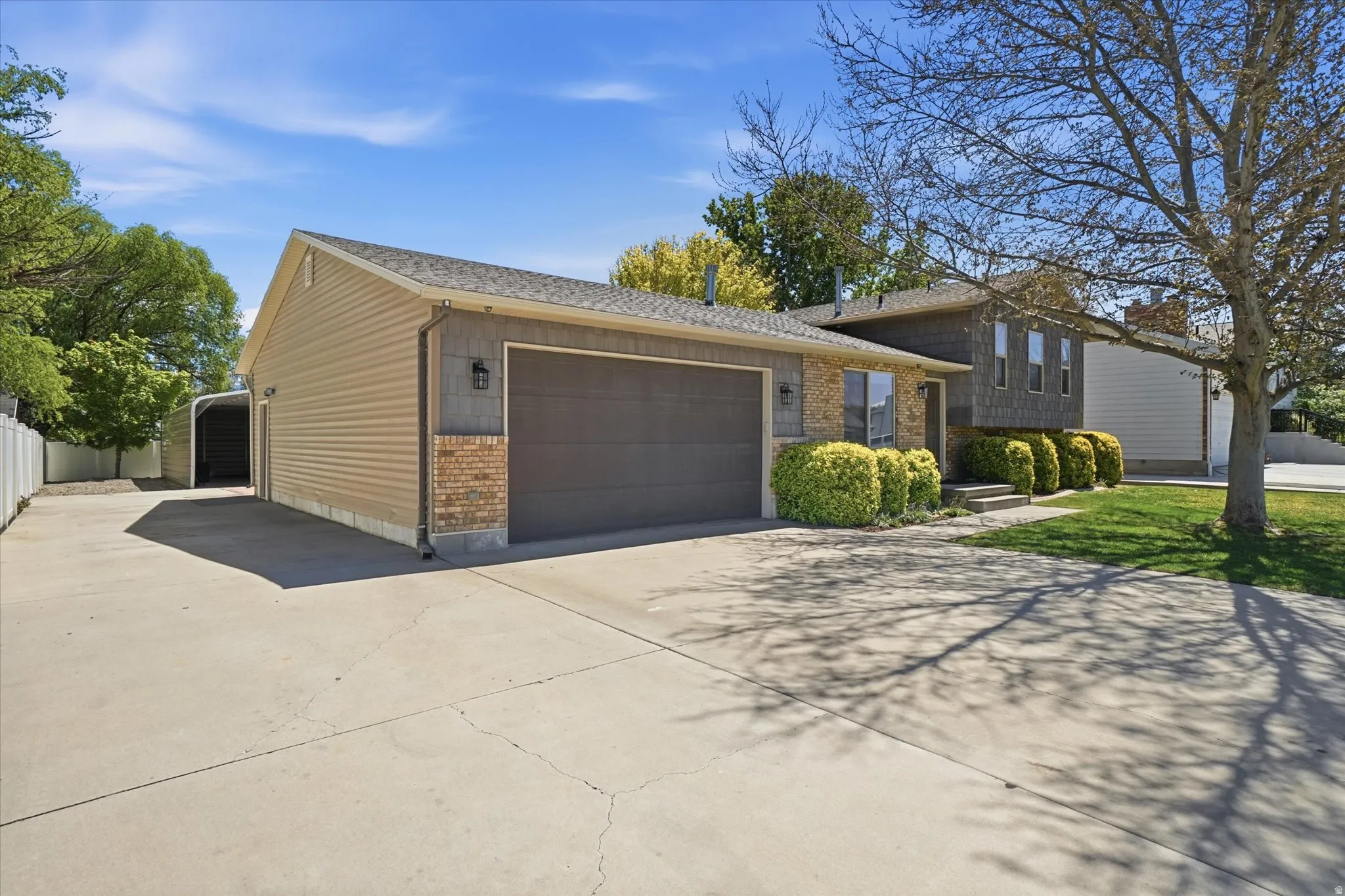 Split level home featuring concrete driveway, an attached garage, brick siding, and roof with shingles