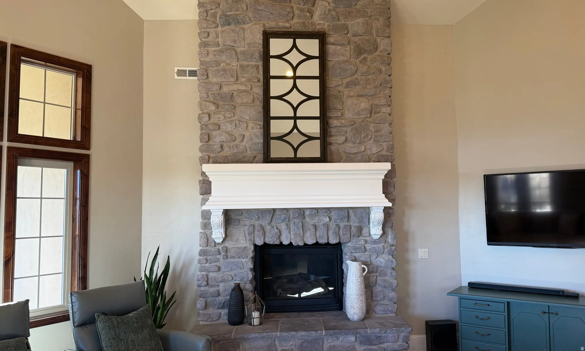 Stone-faced fireplace with a white mantelpiece featuring decorative corbels